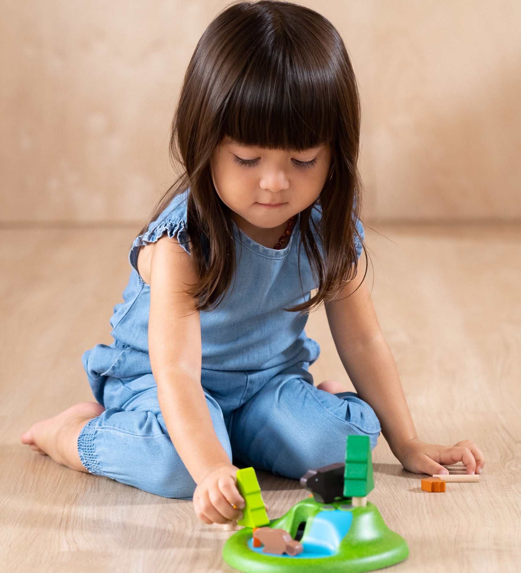 A child playing with the The PlanToys Animal Set on a wooden floor. 