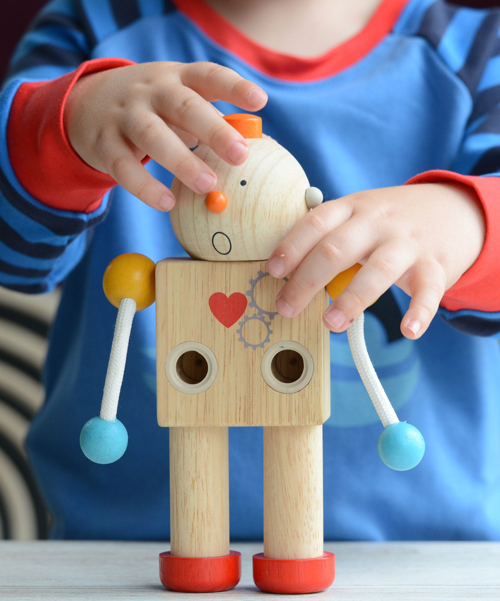 A child placing the round head with a shocked expression on the PlanToys Build a Robot. 