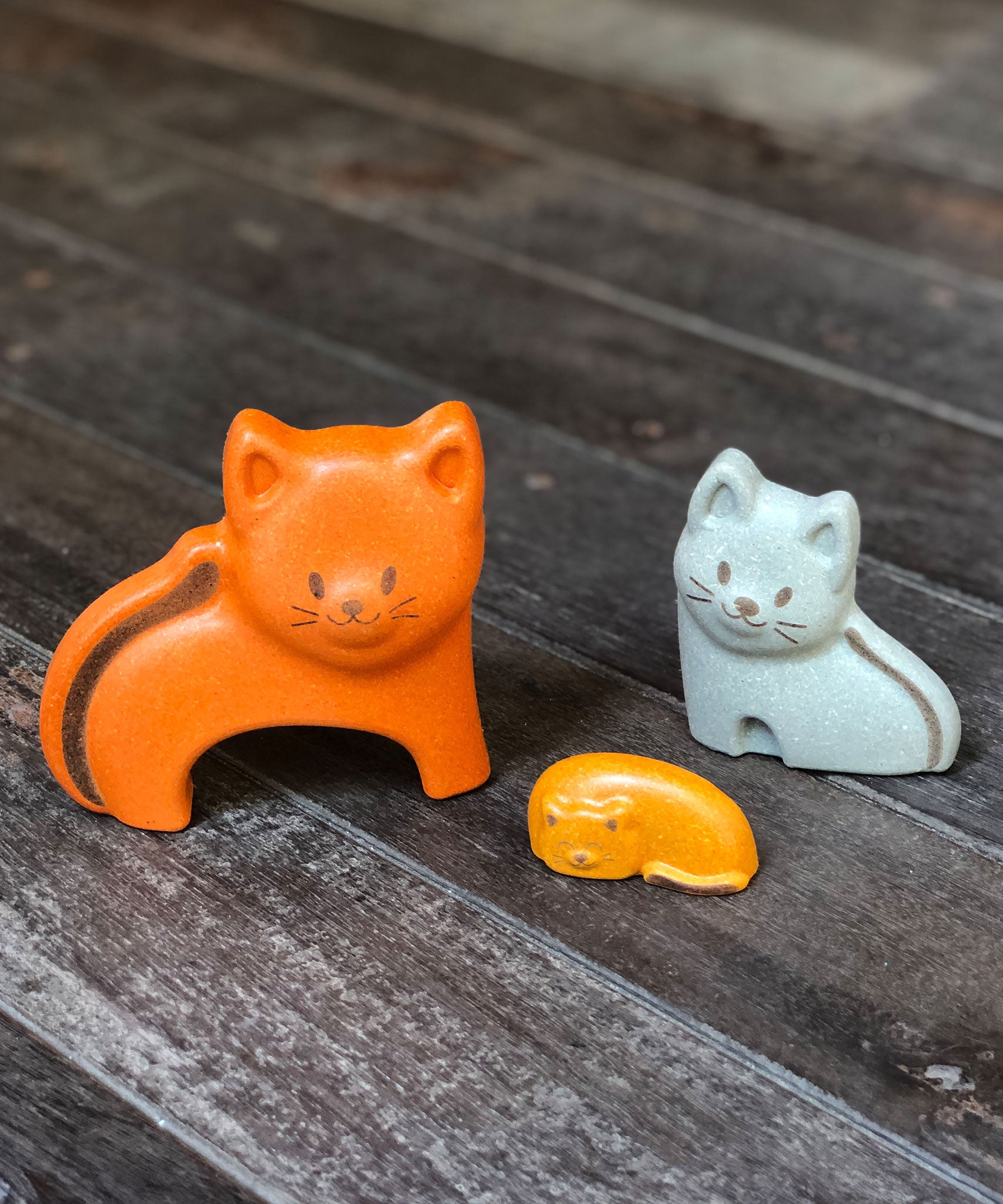 The three cat figures from the PlanToys Cat Puzzle on a wooden surface.