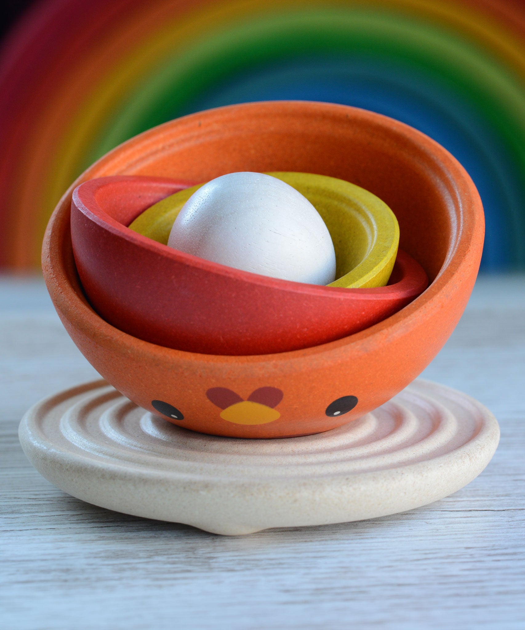 The PlanToys Chicken Nesting Toy shown with all the pieces nested inside each other on the wooden base. 