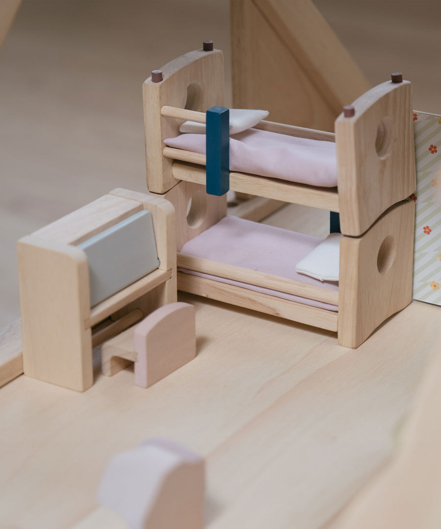 The bunk beds and the writing desk from the Plan Toys Children's Room Dolls House Furniture Set placed in a room in a dolls house. 
