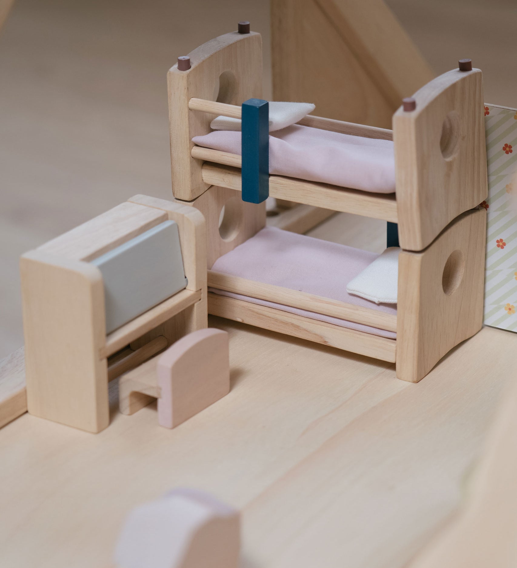 The bunk beds and the writing desk from the Plan Toys Children's Room Dolls House Furniture Set placed in a room in a dolls house. 
