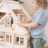 Close up of young child playing with toy dolls inside the PlanToys plastic-free first dolls house toy set