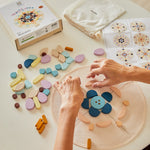 Close up of some hands arranging the PlanToys wooden mandala toy blocks on a white table cloth