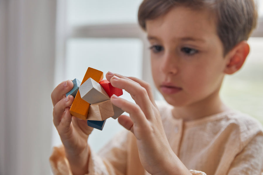 Close up of young boy looking at the PlanToys Waldorf toy block puzzle