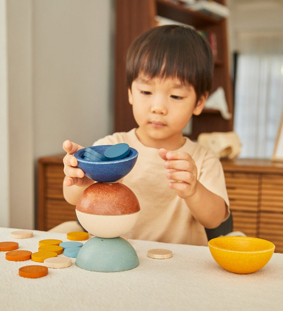 Young child stacking the PlanToys wooden orchard sort and count cups on a table