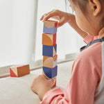 Close up of young girl stacking up the PlanToys childrens plastic-free geo blocks on a white window sill