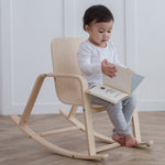 A child sitting on a PlanToys children's Rocking Chair. 