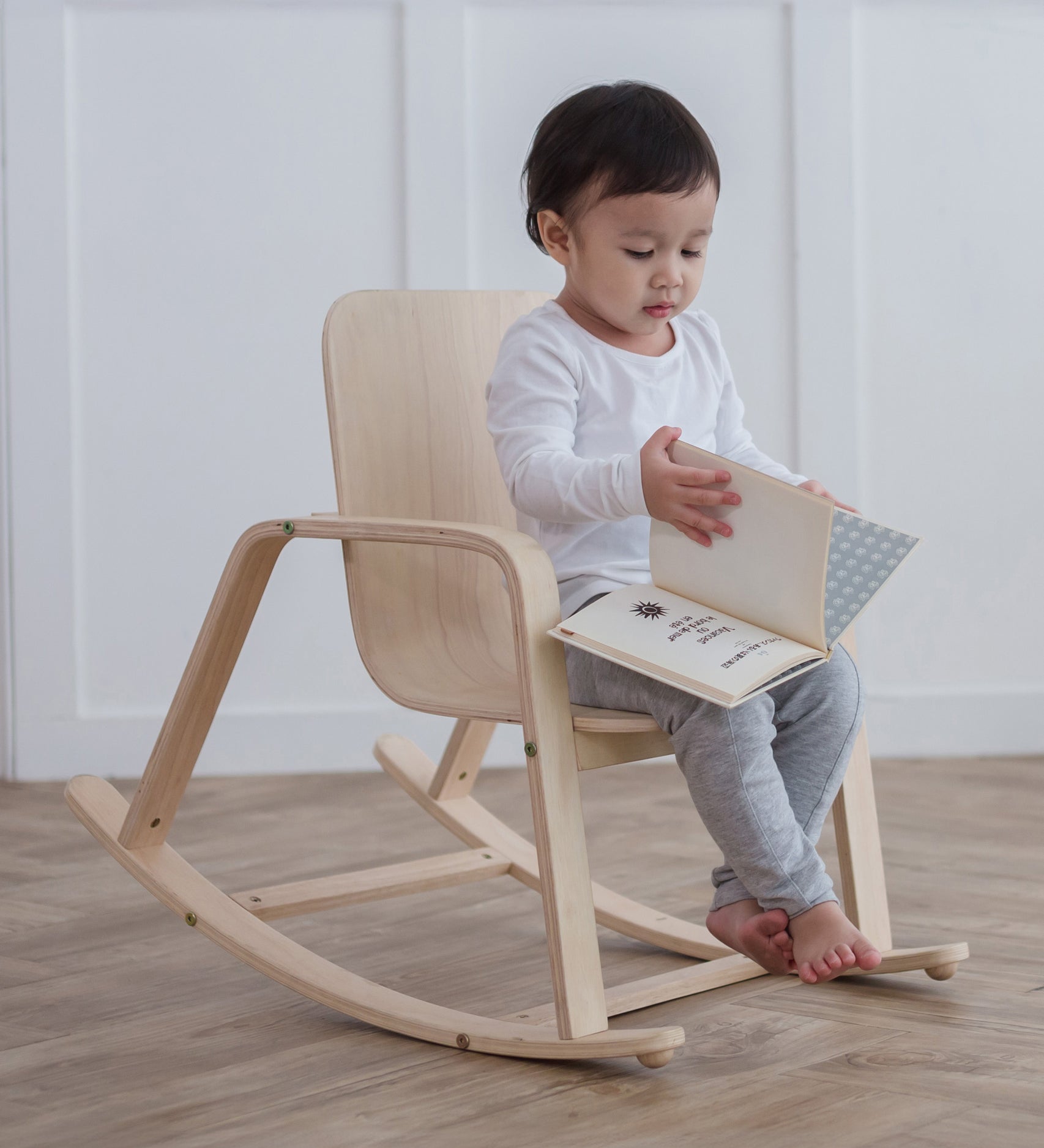 A child sitting on a PlanToys children's Rocking Chair. 