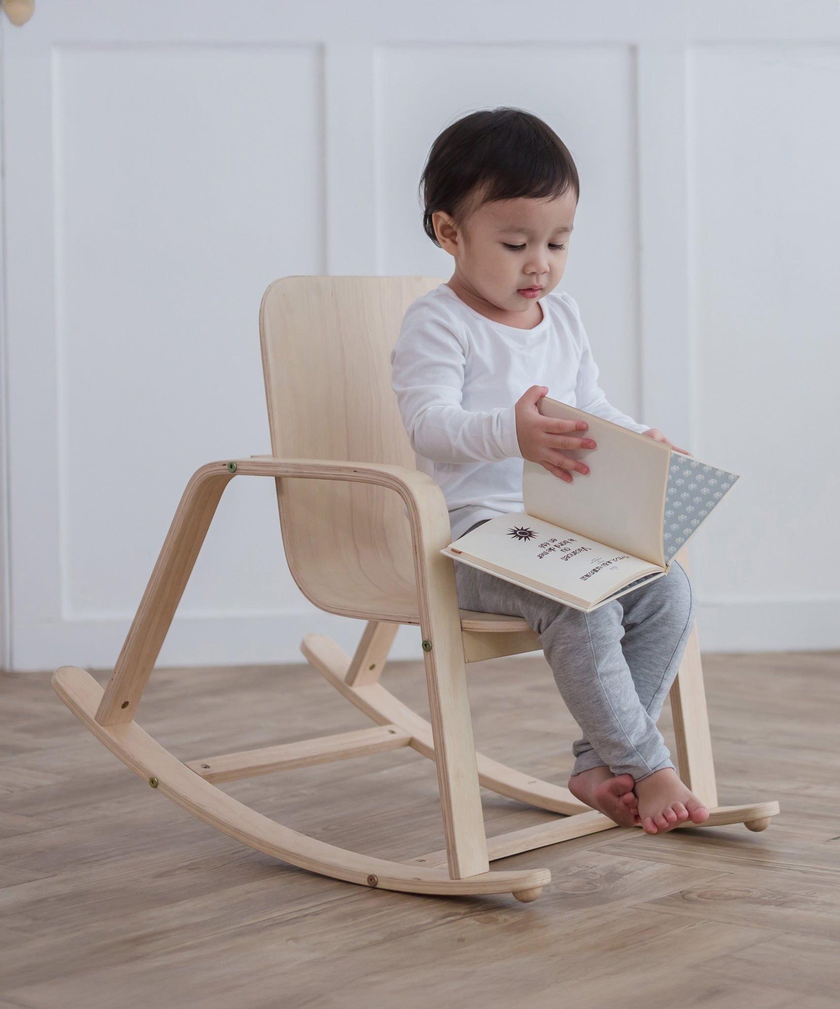 A child sitting on a PlanToys children's Rocking Chair. 