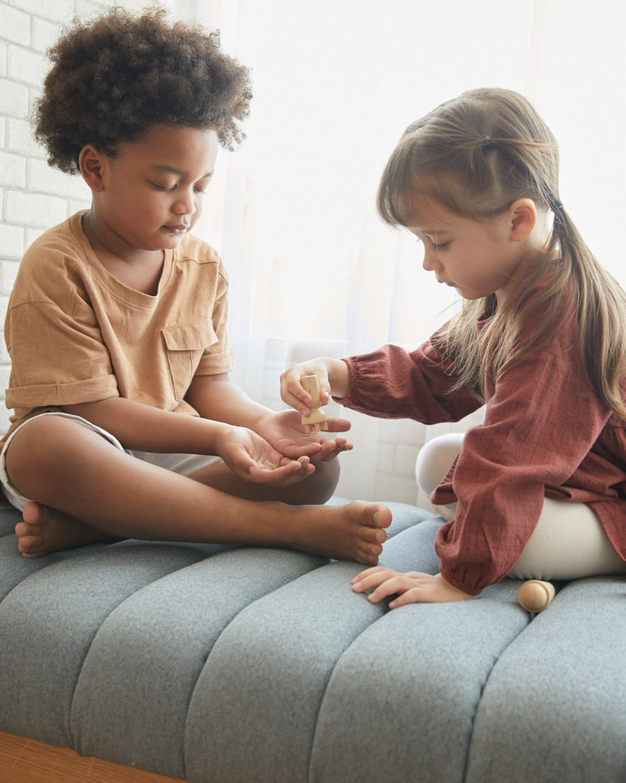 playing with the PlanToys sensory touch and guess game on a grey sofa