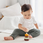 Young boy playing with the PlanToys Waldorf stacking rings toy on a white bed