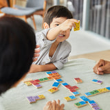 Young boy smiling and holding up a piece of the PlanToys wooden mood dominos game