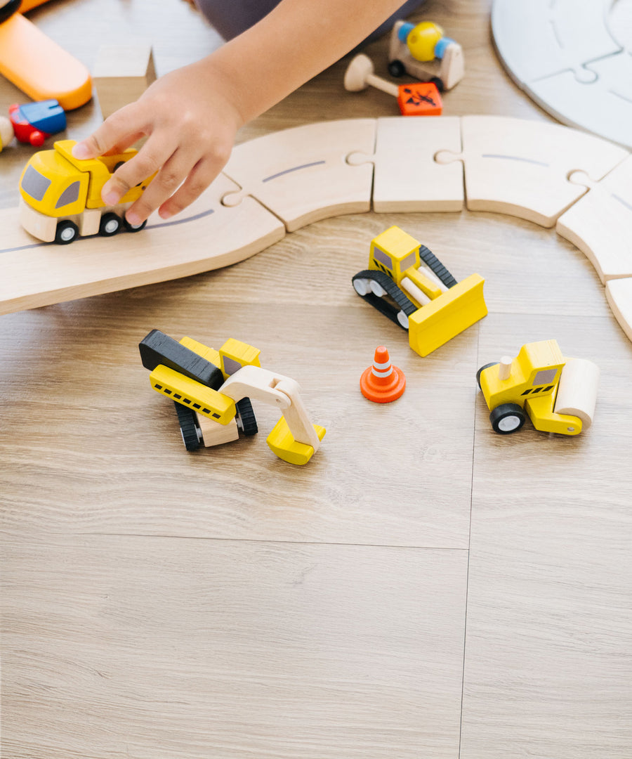 A close up of a child playing with the PlanToys Road Construction Set.