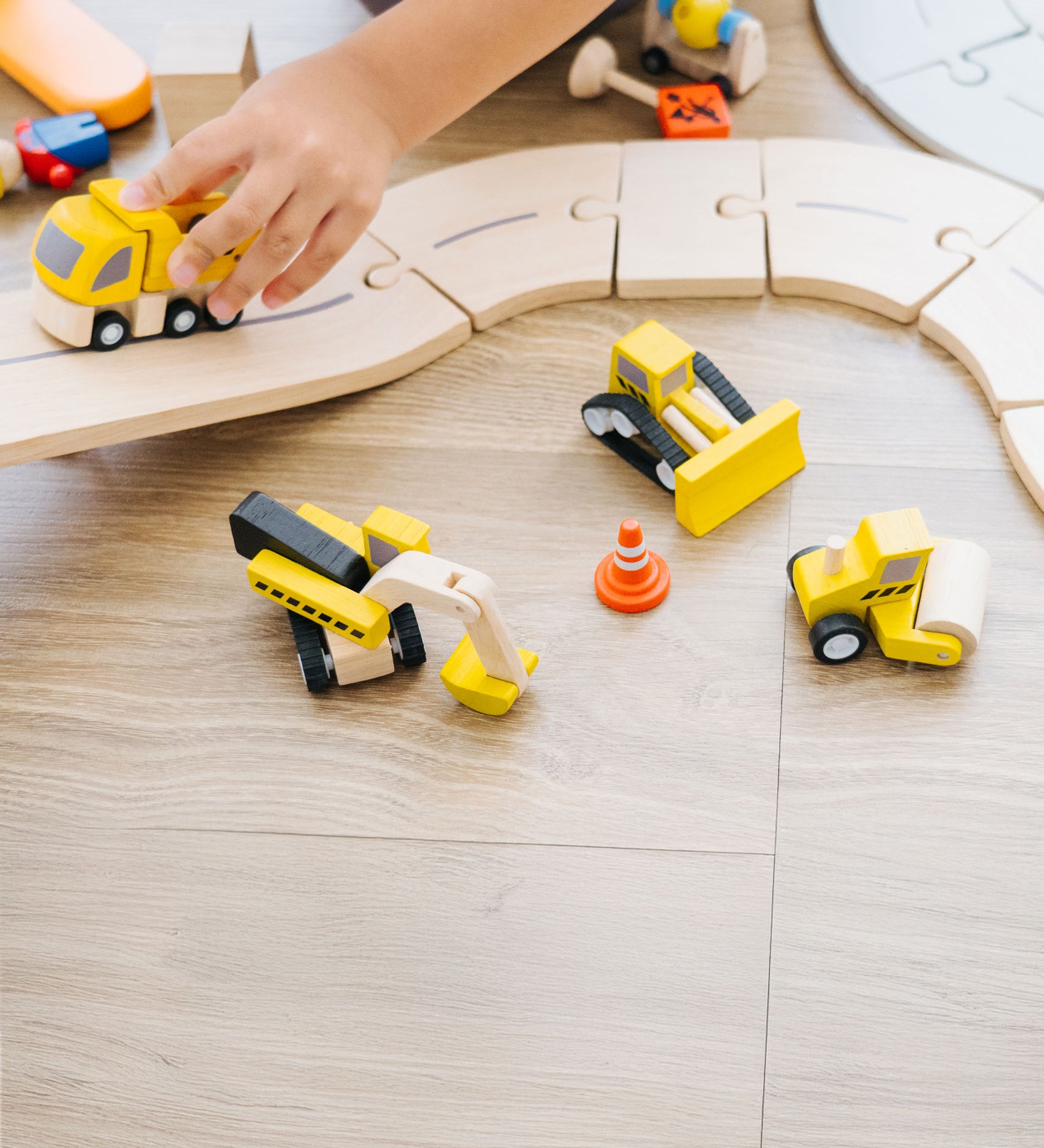 A close up of a child playing with the PlanToys Road Construction Set.