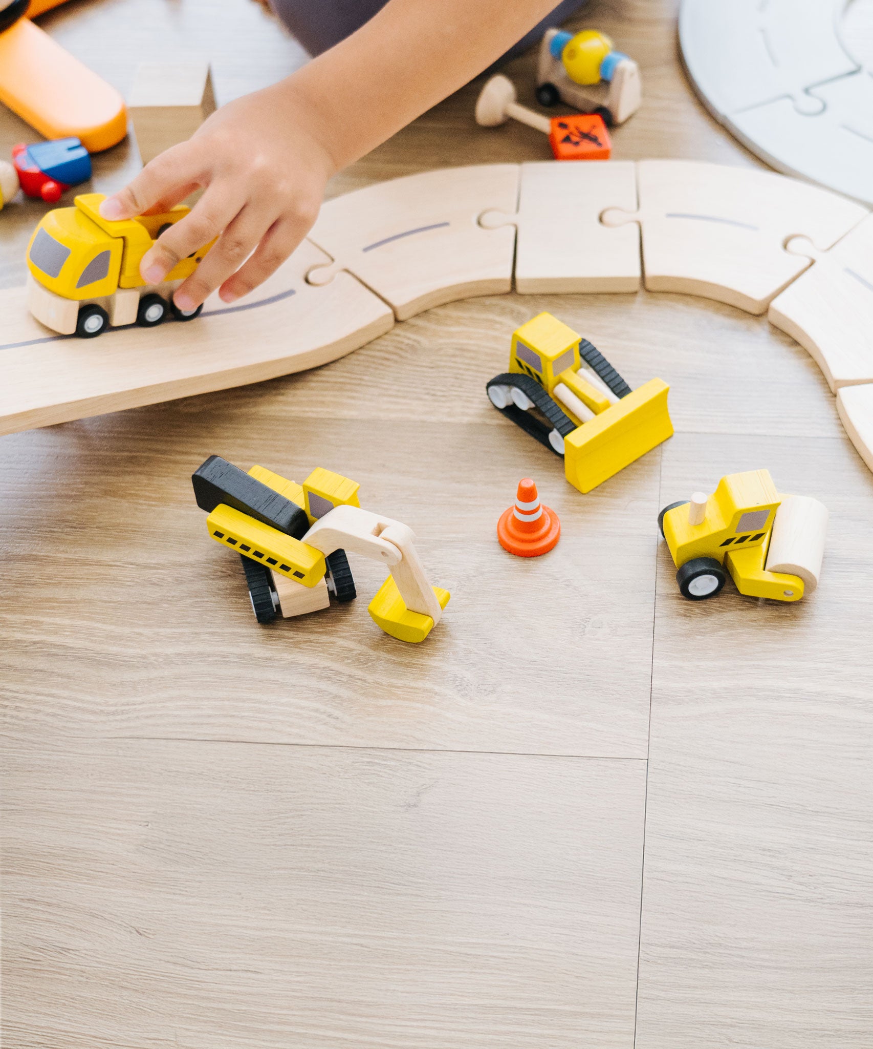 A close up of a child playing with the PlanToys Road Construction Set.