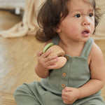 Close up of young girl sat down holding the PlanToys wooden clapping roller sensory toy