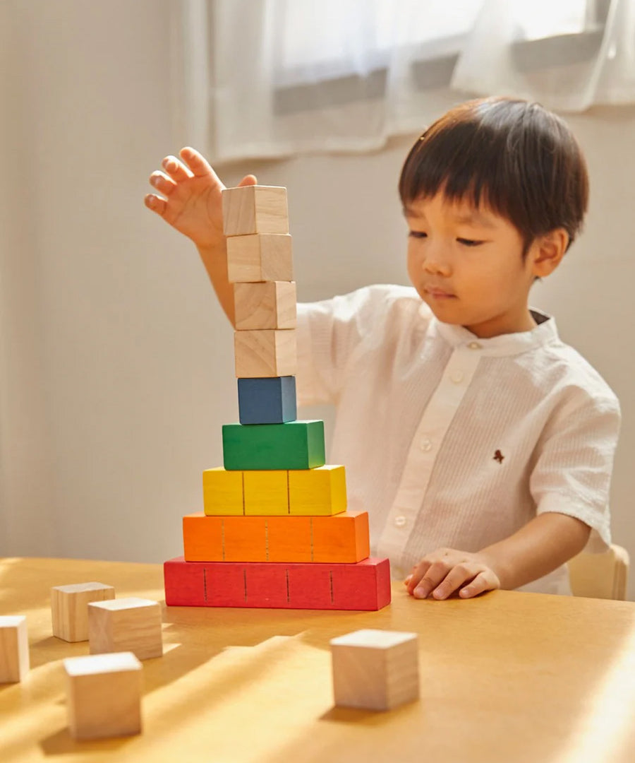 A young child sat at a table stacking the PlanToys plastic-free wooden counting cubes. 