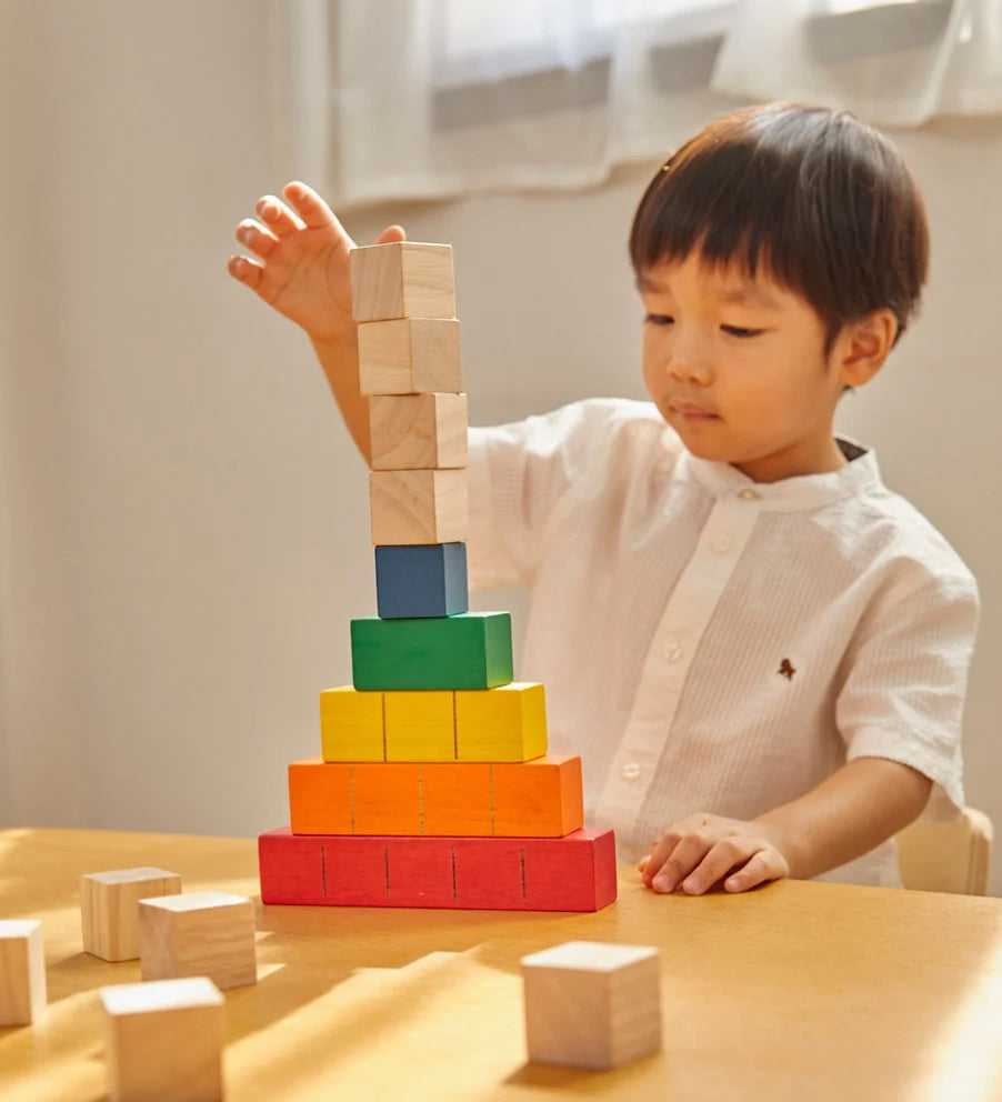 A young child sat at a table stacking the PlanToys plastic-free wooden counting cubes. 