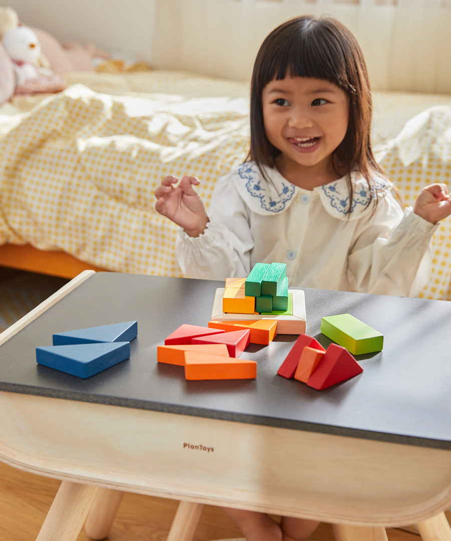 A child sat at the PlanToys desk playing with the PlanToys Coloured Fraction Blocks set. 