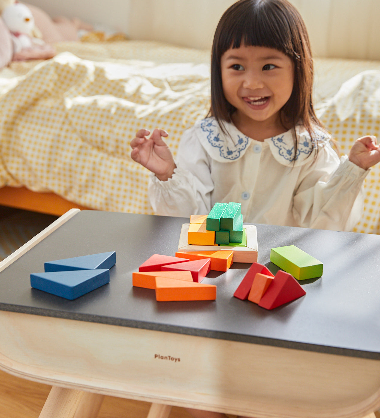 A child sat at the PlanToys desk playing with the PlanToys Coloured Fraction Blocks set. 