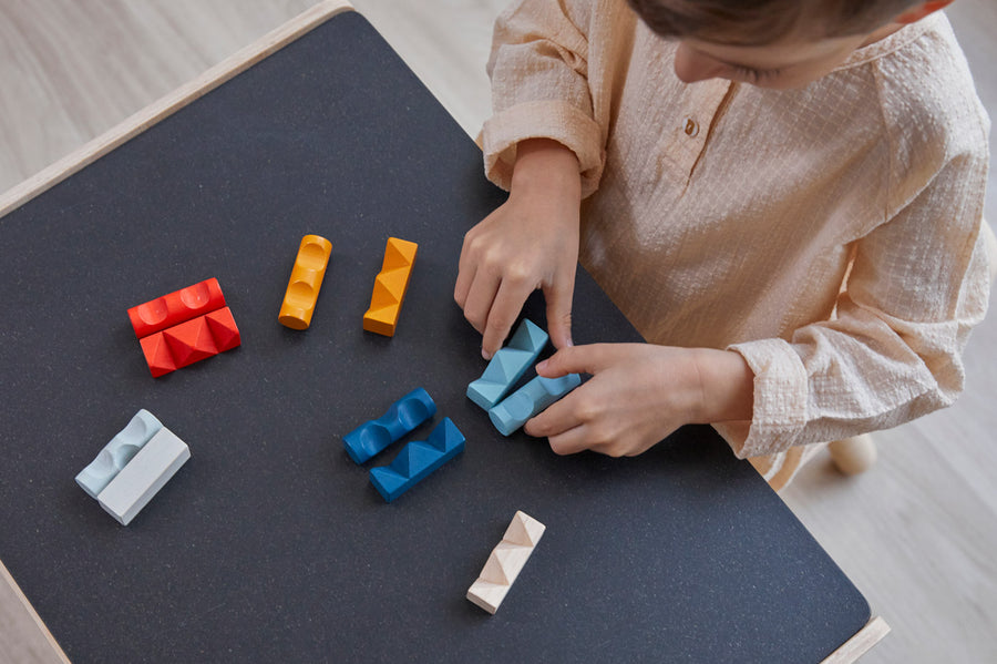 Boy ordering pieces of the PlanToys wooden toy block puzzles in order of their colour