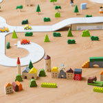 The PlanToys Countryside Blocks Set placed on the floor in a small world play set up with the PlanToys rubber road. 