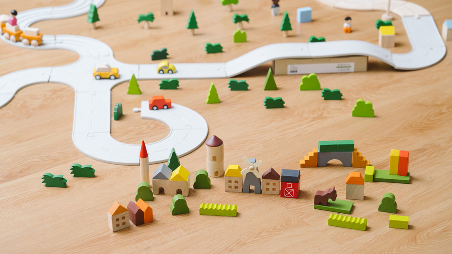 The PlanToys Countryside Blocks Set placed on the floor in a small world play set up with the PlanToys rubber road. 