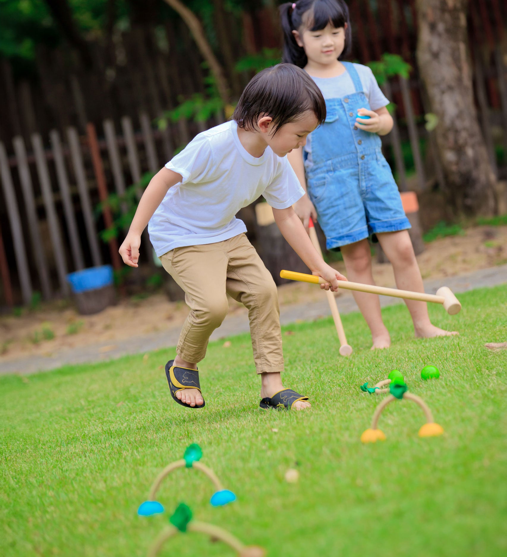 Two children playing with the PlanToys Croquet set outdoors. 