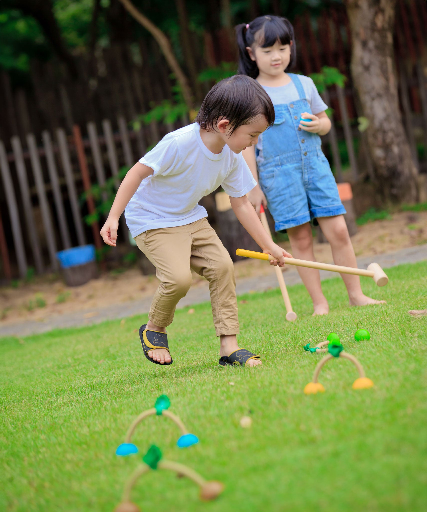 Two children playing with the PlanToys Croquet set outdoors. 