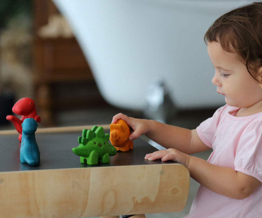 A child playing with the PlanToys Dino Set on a PlanToys desk. 