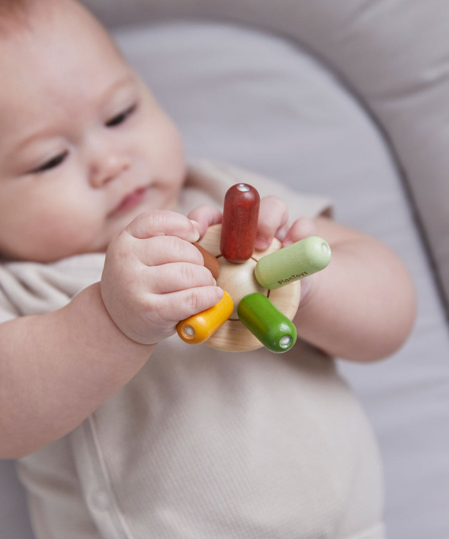 Close up of a baby's hand  holding the PlanToys flexi jellyfish baby teething toy. 