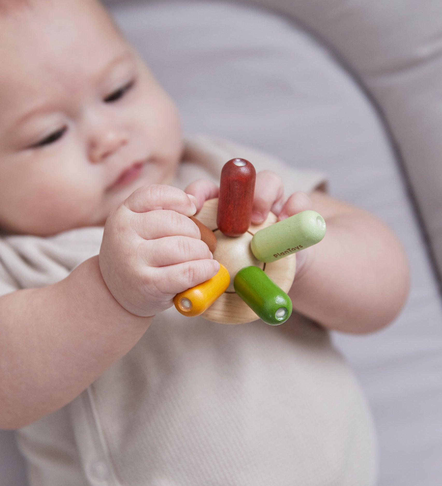 Close up of a baby's hand  holding the PlanToys flexi jellyfish baby teething toy. 