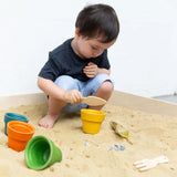 A child playing in a sand pit with the PlanToys flower pots. 