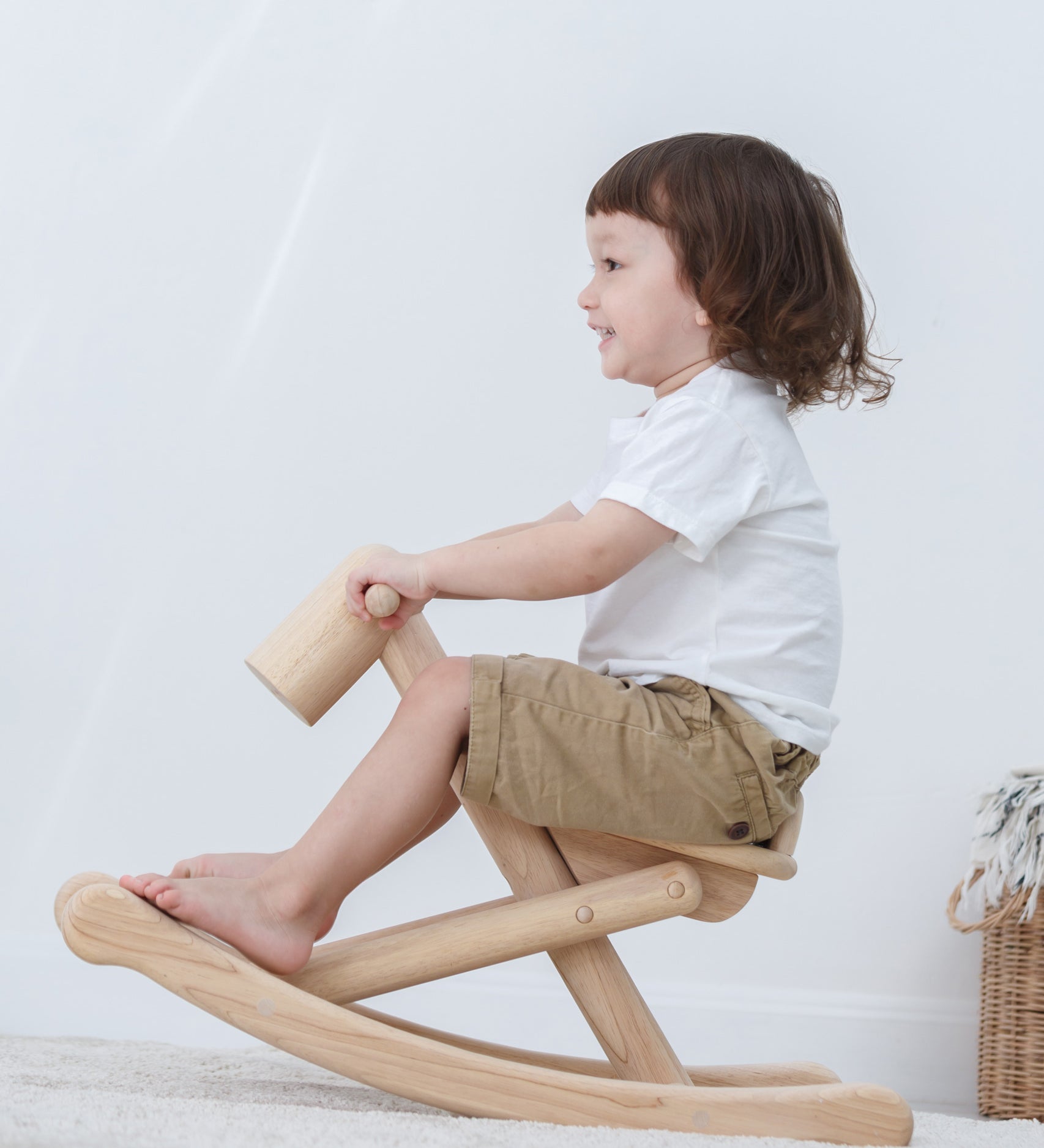 A child is rocking on the PlanToys Foldable Rocking Horse, their feet are placed on the frame at the bottom.