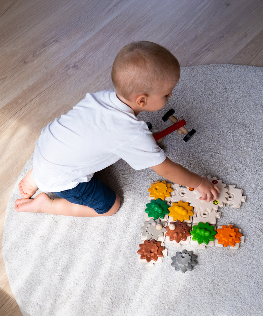 An overhead view of a child playing with the PlanToys Gear and Puzzle toy. 