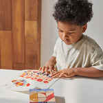 Close up of boy looking at different patterns to make with the PlanToys stacking geo pattern blocks on a white table.