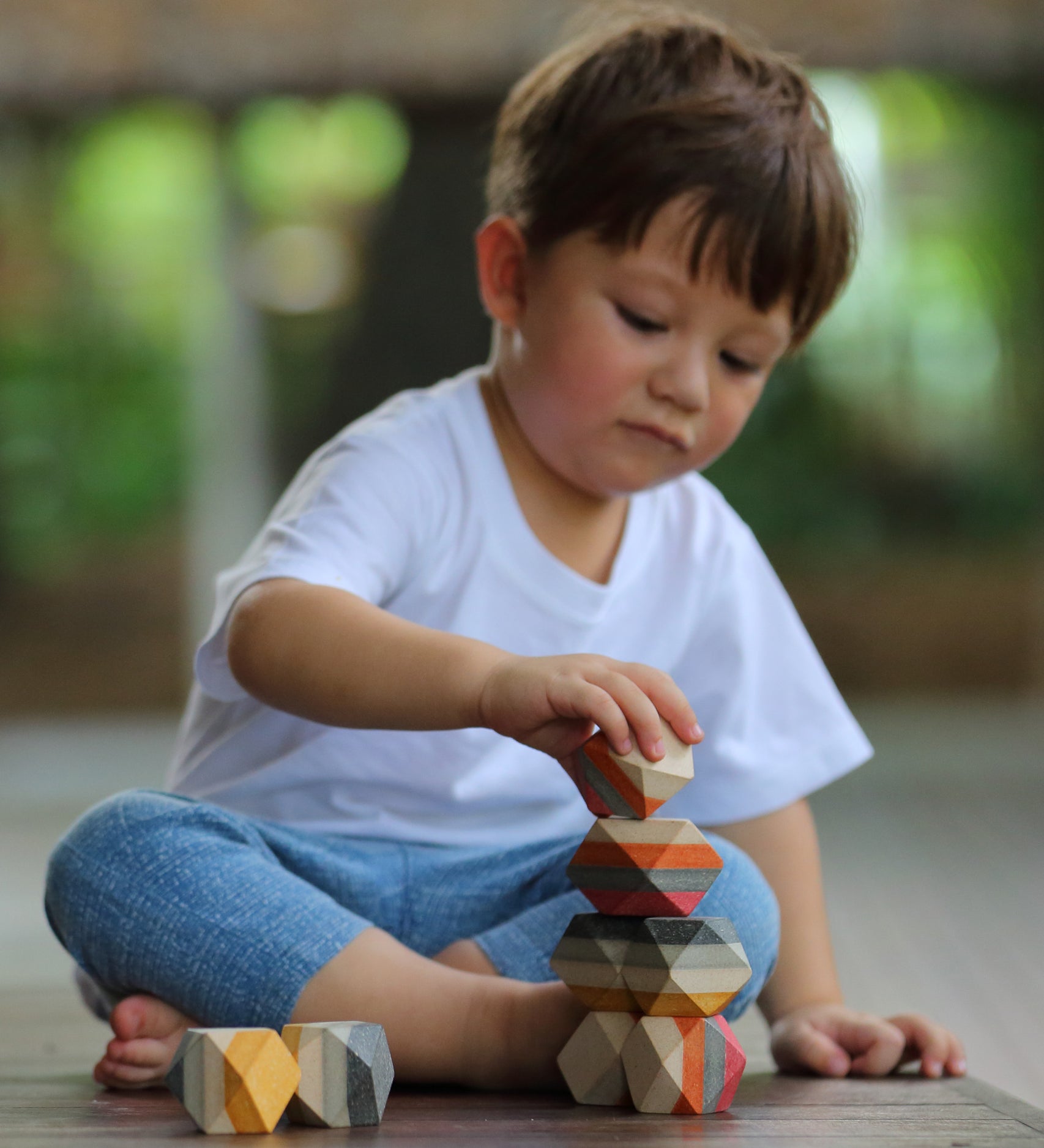 A child playing with the PlanToys Geo Stacking Rocks.