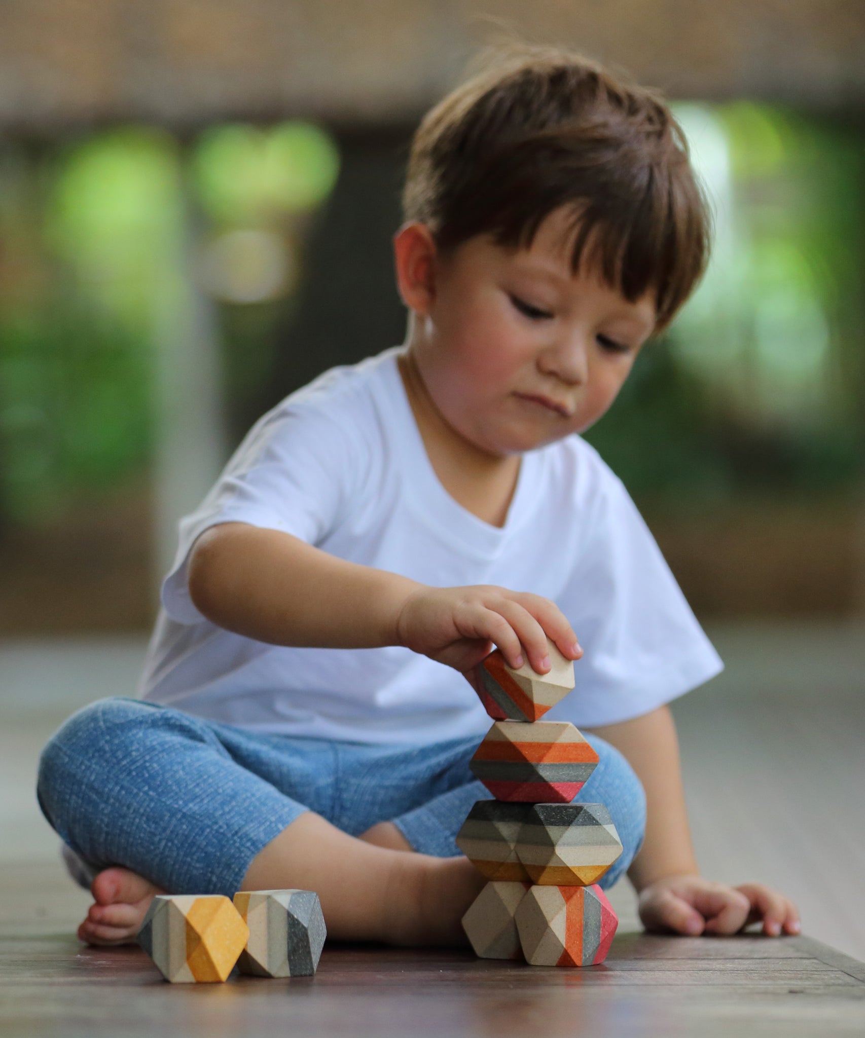 A child playing with the PlanToys Geo Stacking Rocks.