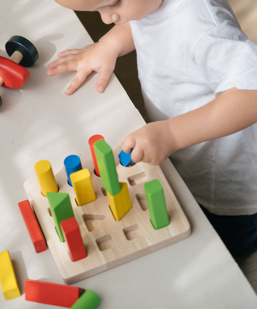 A child playing with the PlanToys Geometric Peg Board.