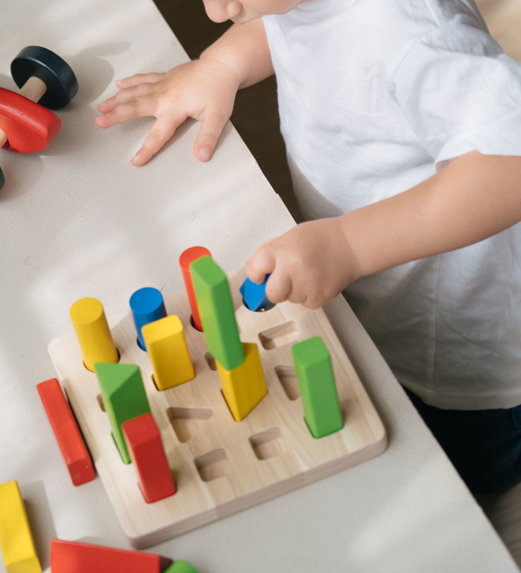 A child playing with the PlanToys Geometric Peg Board.