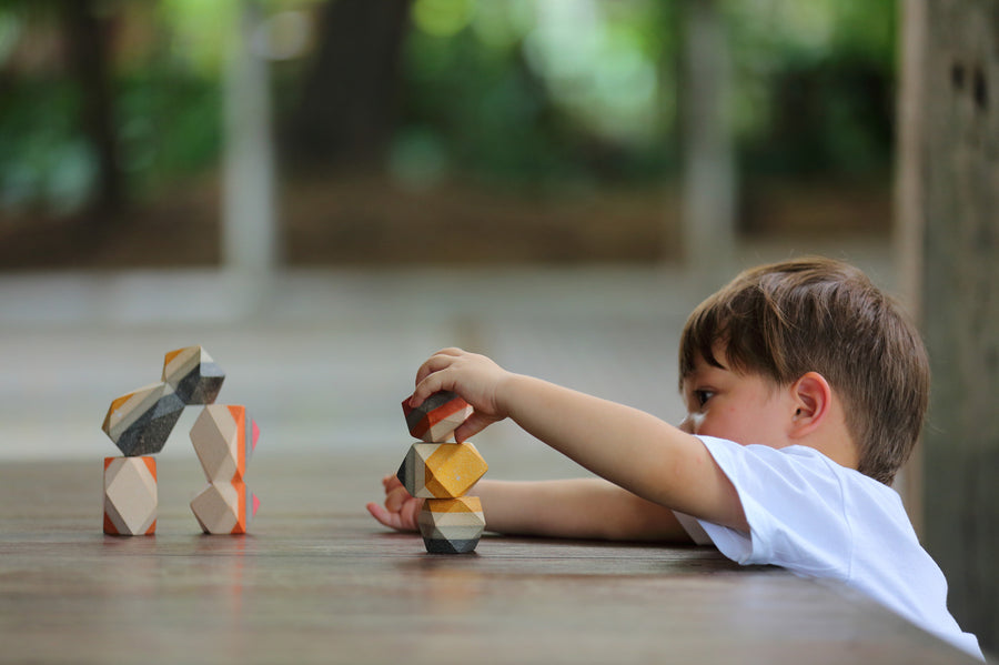 A child playing with the PlanToys Geo Stacking Rocks. They are stacking the rocks on top of each other. 