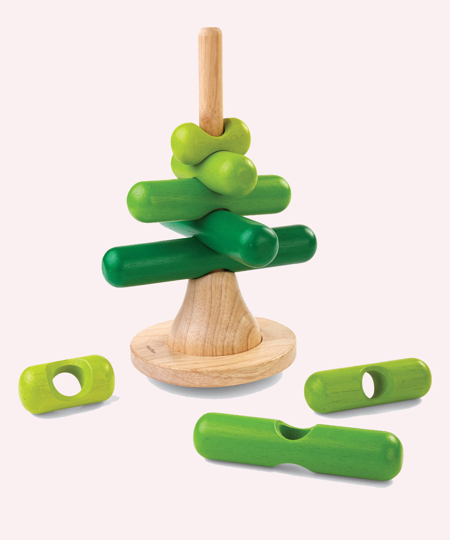 The PlanToys Stacking Tree Wooden Toy on a plain background. Three pieces have been taken off the base piece and placed besides the base. 