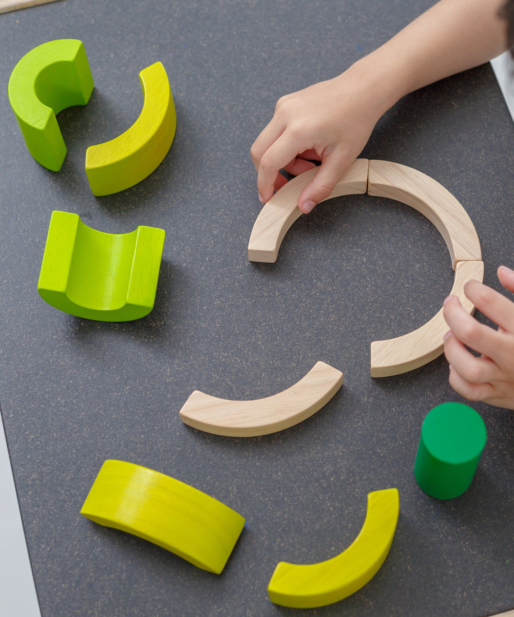 A close up of PlanToys Curve Blocks being played with by a child. 