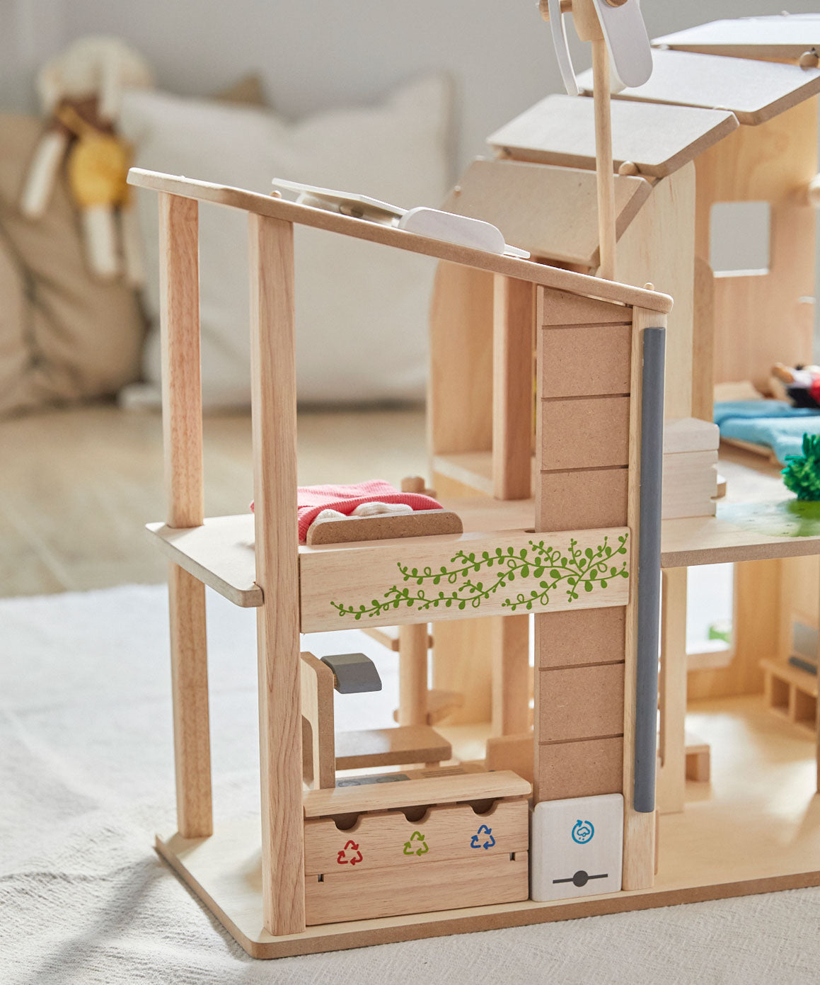 A close up of the recycling area at the side of the PlanToys Green Dolls' House. There are three compartments for recycling next to a rain water harvester. 