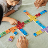 Close up of a family sat around the PlanToys rainbow wooden mood dominos game on a grey tablecloth