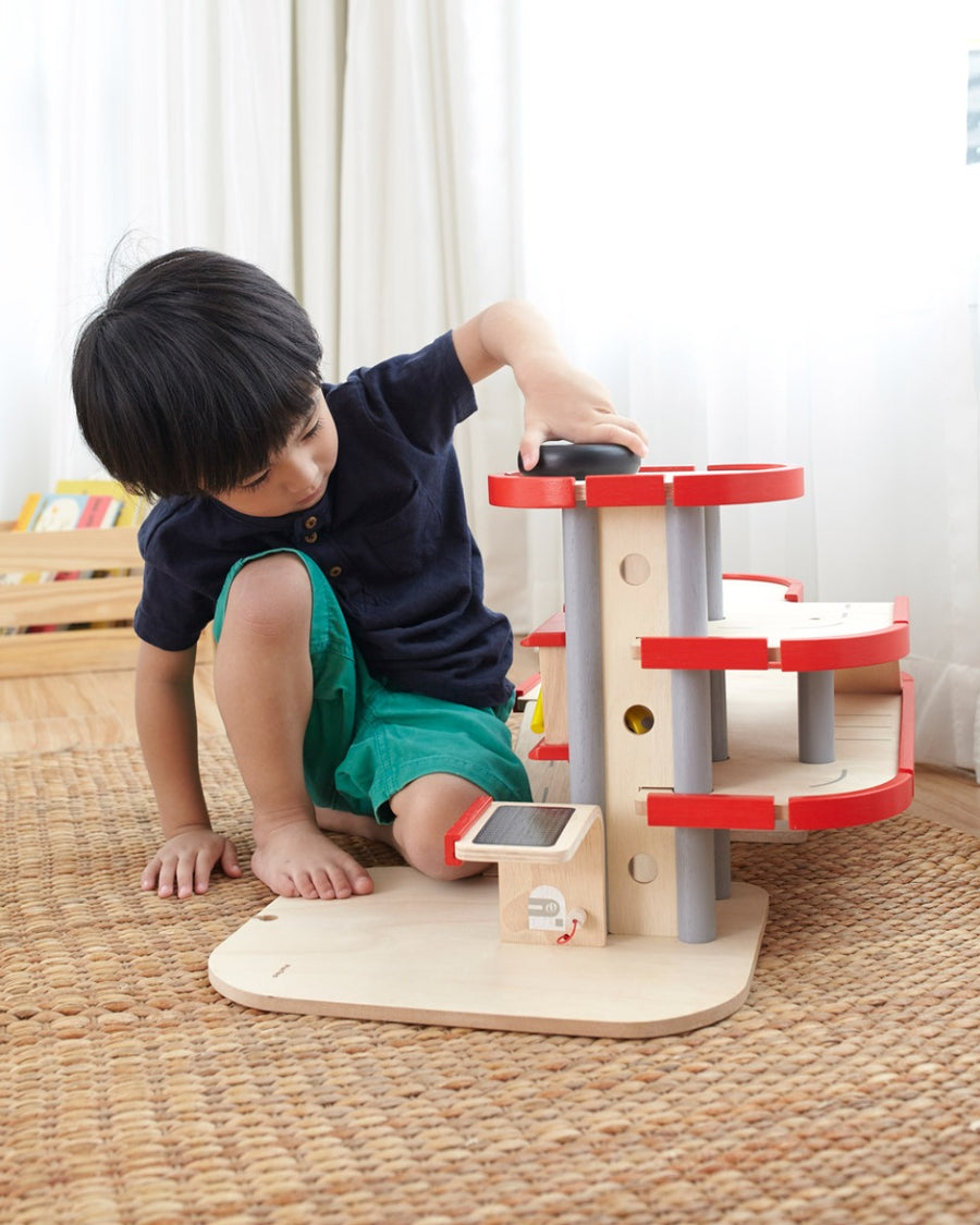 A child playing with the PlanToys PlanWorld Parking Garage.