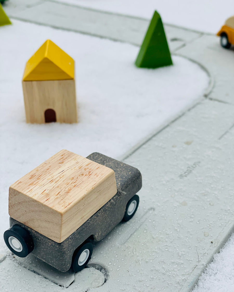 Close up of the PlanToys grey wagon toy car on the PlanToys rubber road and rail set