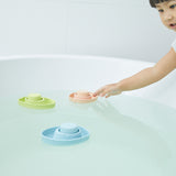 Girl reaching out to touch a PlanToys natural rubber boat toy in a bath tub