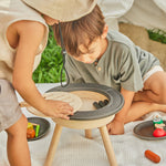 Close up of two children crouched around the PlanToys BBQ toy